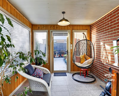 Bright sunroom featuring a cozy seating area and access to a beautifully landscaped outdoor space.