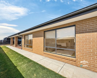 Modern brick home featuring large windows and a spacious yard, perfect for outdoor activities and natural light.