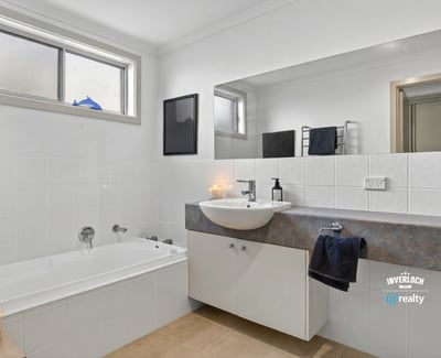 Modern bathroom featuring a spacious tub, sleek countertop, and ample natural light from large windows.