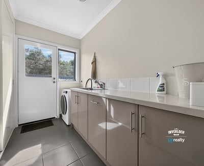 Bright laundry area featuring modern cabinets, ample counter space, and convenient outdoor access.
