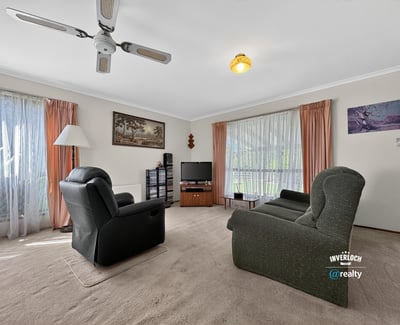Spacious living room featuring large windows, comfortable seating, and a light-filled atmosphere, perfect for relaxation.