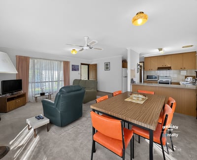 Spacious living area with natural light, featuring a dining space and a functional kitchen layout.