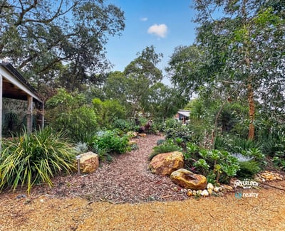 This landscaped garden features diverse plantings and unique stone accents, creating a vibrant outdoor oasis.