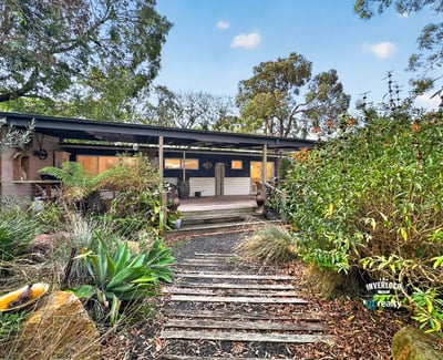 This inviting home features a spacious front porch and lush gardens, perfect for outdoor relaxation.