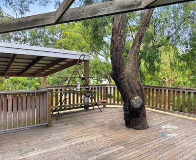 Spacious deck surrounded by lush greenery, perfect for outdoor gatherings and relaxation in nature.