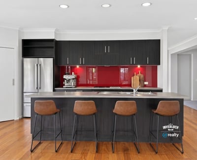 Modern kitchen featuring sleek cabinetry, a striking red backsplash, and spacious island with bar seating.