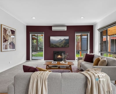 Cozy living room with modern features, featuring a fireplace and large windows overlooking a private outdoor space.