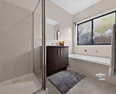 Modern bathroom featuring a spacious shower, separate tub, and large window for natural light.