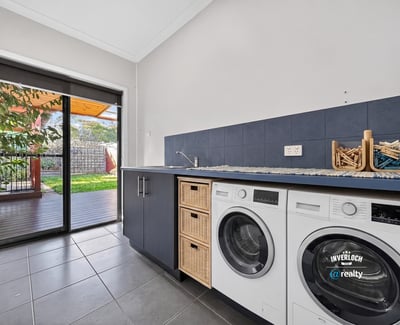 Bright laundry room featuring modern appliances and direct access to a shaded outdoor area.