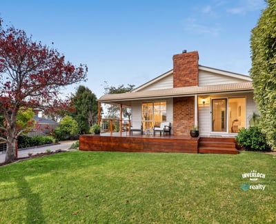 Nestled on a spacious lawn, this home features a welcoming porch and abundant outdoor greenery.