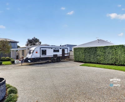 Spacious driveway perfectly accommodates an RV, surrounded by well-maintained landscaping for added privacy and convenience.