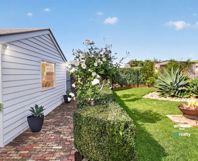 Discover a well-maintained outdoor space featuring lush greenery and a cozy fire pit for gatherings.