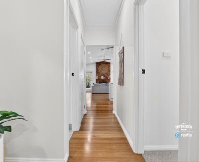 Bright, inviting hallway leading to a spacious living area, showcasing modern design and warmth throughout.
