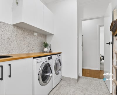 Bright laundry area featuring modern appliances, streamlined cabinetry, and a clean, functional design.