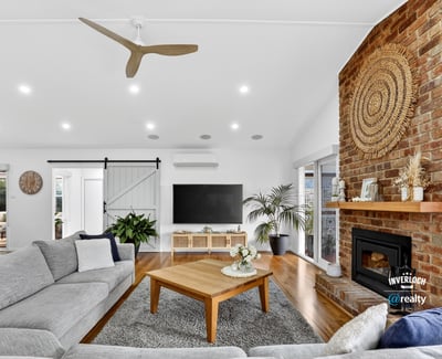 Bright and inviting living space featuring a striking brick fireplace and modern ceiling fan, perfect for gatherings.