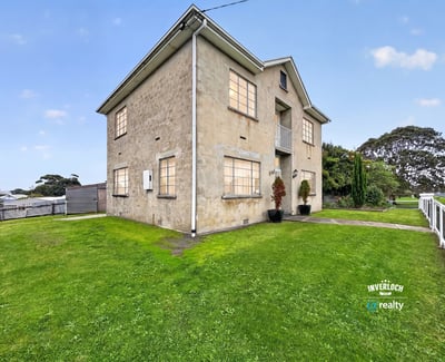 Spacious multi-level property on a generous lot, featuring large windows and expansive green yard.