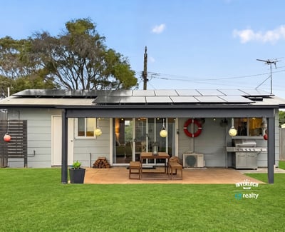 This modern home features a spacious outdoor area with solar panels and a built-in grill for entertaining.