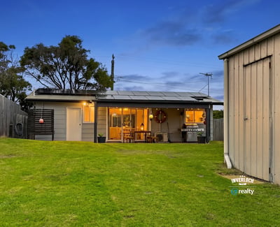 This inviting home features spacious green yard, modern amenities, and a cozy outdoor living area.