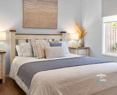 Bright and inviting bedroom features coastal decor, cozy bedding, and natural light streaming through the window.