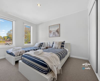 Bright and inviting bedroom with ample natural light, featuring twin beds and modern aesthetics.