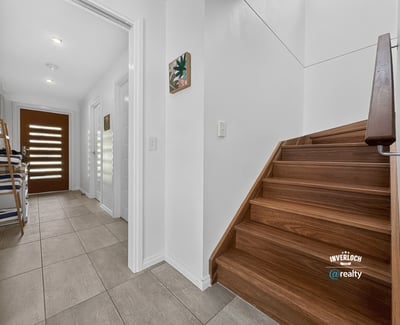 Modern entryway featuring open space, inviting natural light, and a warm wooden staircase.