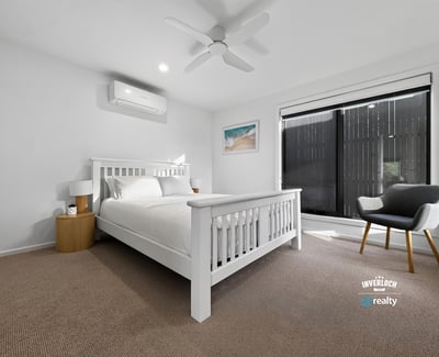 Bright and airy bedroom featuring large windows, modern furnishings, and a cozy atmosphere for relaxation.