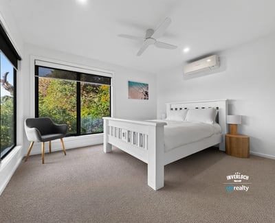 Bright bedroom with large windows showcasing natural light and leafy views, featuring modern finishes and comfort.