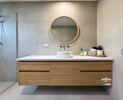 Discover a modern bathroom featuring sleek cabinetry, a striking round mirror, and contemporary fixtures.