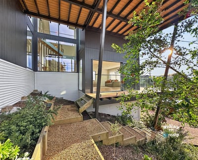 Contemporary home featuring expansive windows, a spacious deck, and beautifully landscaped outdoor areas for relaxation.
