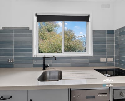 Modern kitchen featuring sleek countertops and a large window that offers refreshing garden views.
