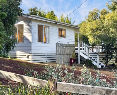 This inviting home features ample windows, a spacious outdoor area, and a welcoming front porch.