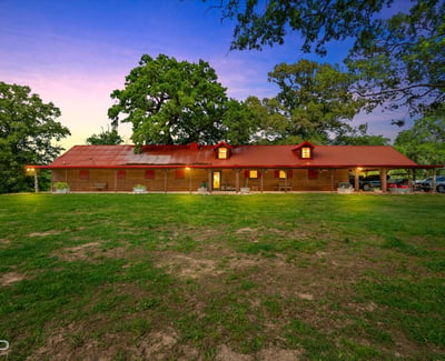 Discover this spacious home set on a sprawling green lot, featuring a distinctive red roof and open outdoor space.