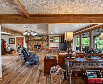 Spacious living area with a rustic fireplace, natural light, and inviting views of the outdoors.
