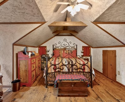 Cozy attic bedroom featuring unique architecture, rustic decor, and ample storage options for personal belongings.