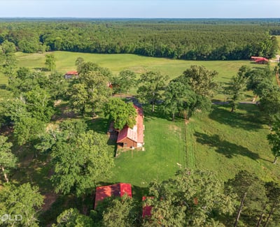 Spacious property featuring a cozy home surrounded by lush greenery and expansive fields, perfect for outdoor enthusiasts.
