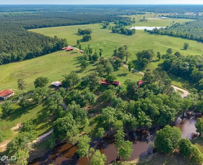 Expansive rural property featuring lush pastures, scenic water views, and multiple outbuildings for versatile use.