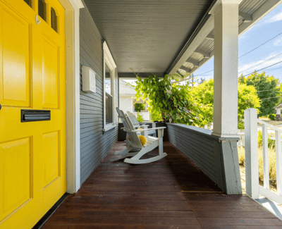 Welcoming porch featuring a vibrant yellow door and peaceful seating, perfect for enjoying neighborhood views.