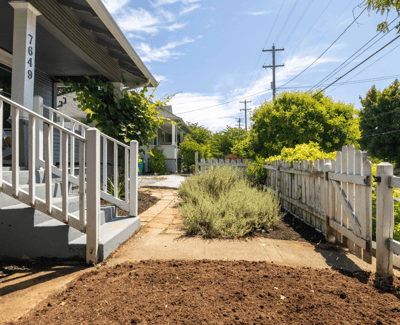 Inviting entryway with landscaped garden beds and a spacious pathway, perfect for outdoor living.