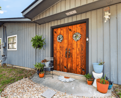Inviting rear entryway featuring distinctive double doors and vibrant planters, perfect for welcoming guests home.