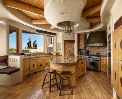 This one-of-a-kind kitchen features curved architecture, natural wood cabinetry, and luxury appliances. A center island and cozy breakfast nook offer a charming place to gather, with sweeping views right from the sink.
