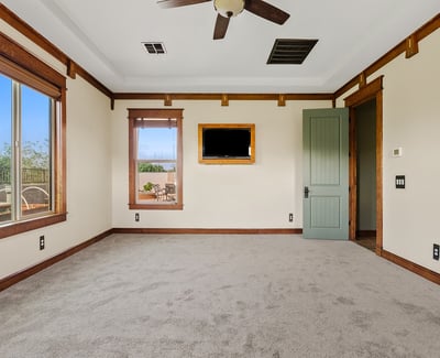 Alternate view of the primary bedroom highlighting tray ceilings, natural light, and refined wood accents. A comfortable and elegant space in this Phoenix home.