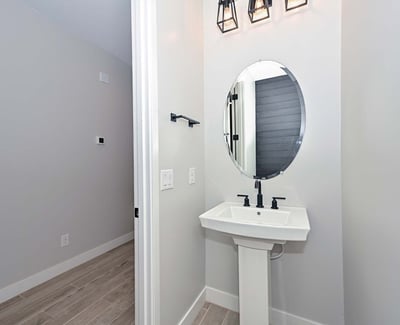 This well-appointed powder room blends modern design with bold light fixtures and clean lines perfect for guests and daily use.