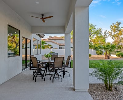 This covered patio space is designed for outdoor comfort, providing shade and style with views of the backyard and pool area.