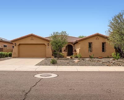 Front elevation with mature trees, desert landscaping, and a two-car garage creates an attractive first impression in this Peoria property.