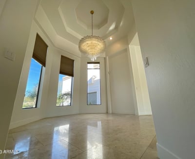 Formal dining area illuminated by a cascading chandelier and framed by tall windows elegant and welcoming.