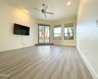 Contemporary living room with modern flooring and panoramic windows overlooking palm trees and lakefront scenery bright and inviting all day long.