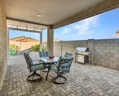 A covered outdoor dining area with paver flooring provides shade and comfort, enhancing everyday living in this Litchfield Park backyard.