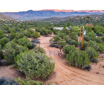 The rustic dual gate sets a charming tone, framed by sweeping mountains and desert foliage. It creates a secure, welcoming transition into this expansive Hackberry property.