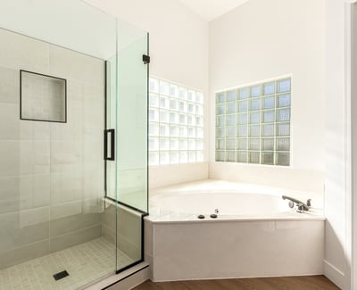 Relaxing Scottsdale bathroom featuring a glass walk-in shower and large soaking tub surrounded by natural light from glass block windows. Modern finishes create a luxurious atmosphere.