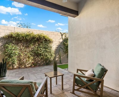 Shaded patio with paver flooring and cozy seating, offering a peaceful outdoor retreat ideal for relaxing or entertaining.